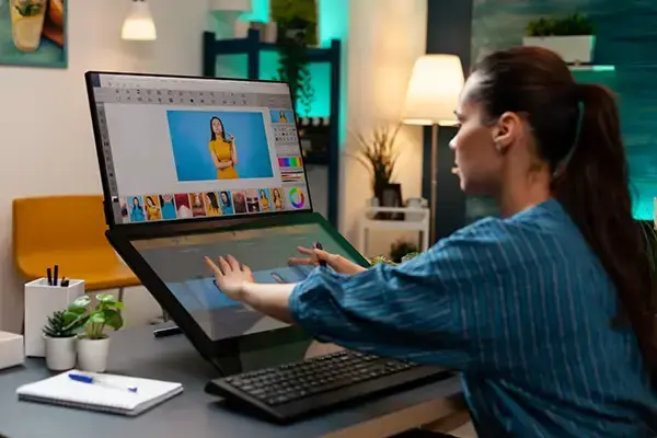 Graphic designer using a digital drawing tablet in a vibrant office setting, editing colorful images.