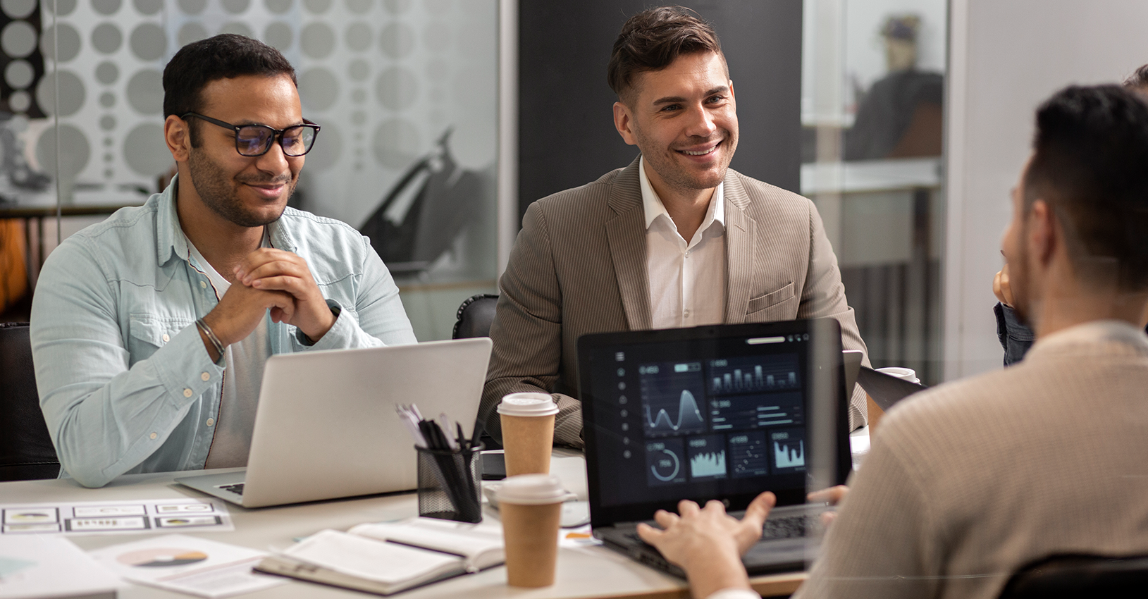 Smiling business professional discussing analytics on a laptop in a modern office setting, highlighting corporate consulting services.