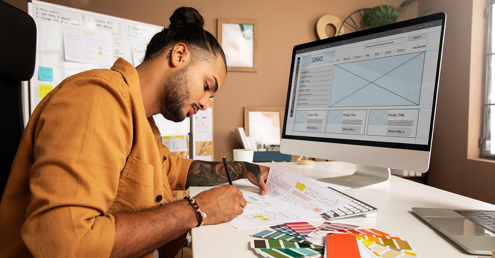 Concentrated male designer sketching logo concepts with color samples on a desk, reflecting the creative process in a modern workspace.